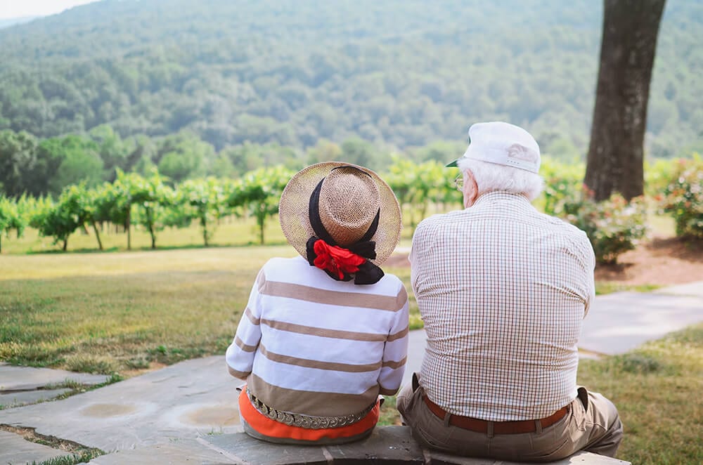 An elderly couple facing away toward a mountain