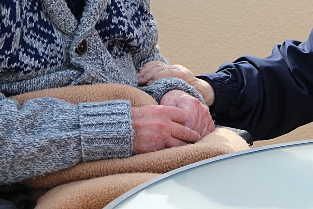 Elderly person holding another elderly person's arm